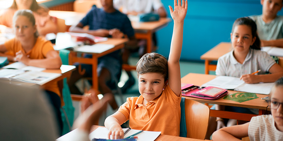 menino com a mão levantada na sala de aula 