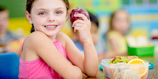 Aluna posa com lanche e Colégio Villa-lobos orienta sobre a importância de uma alimentação saudável. 